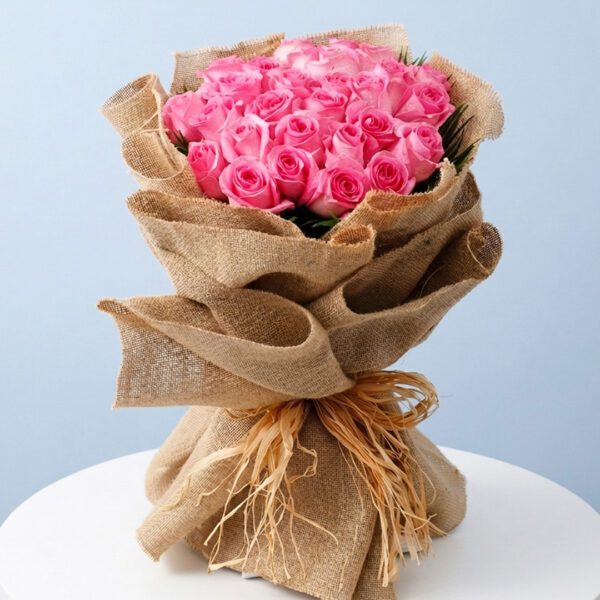 A bouquet of pink roses wrapped in jute, accompanied by a decorative key shaped like a heart.