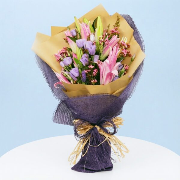 A bouquet of purple and pink flowers wrapped in elegant purple paper, inspired by a wineberry sunset theme.