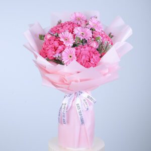 Pink bouquet featuring gerbera daisies, hydrangeas, pink roses, and ferns, elegantly wrapped in pink paper.