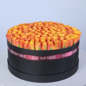 A round black box filled with orange roses, arranged in a circular pattern.