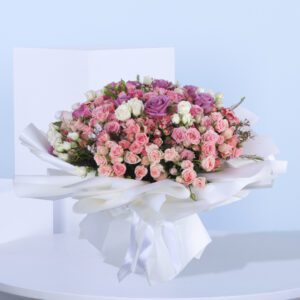 A delightful bouquet of pink and purple roses resting on a white table adding a touch of elegance to the setting.