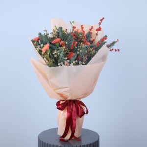 A festive bouquet of carnations, pine, and berries in a kraft paper wrapping with a red ribbon.