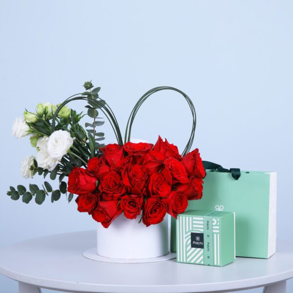 Arrangement of red, white, and green roses in a white box along with two boxes Patchi chocolates.