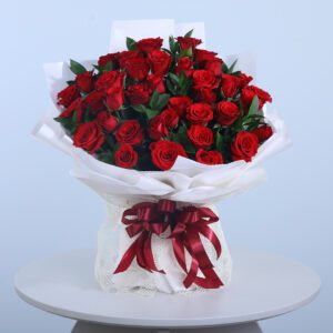 36 red rose bouquet wrapped in white paper with a red ribbon.