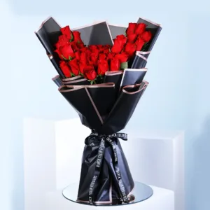 A lavish bouquet of approximately 50 vibrant red roses is elegantly presented. The roses are tightly clustered, showcasing their velvety petals and rich color