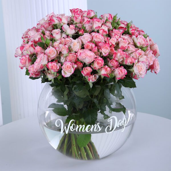 Fifty pink double baby roses arranged in a clear glass fishbowl.