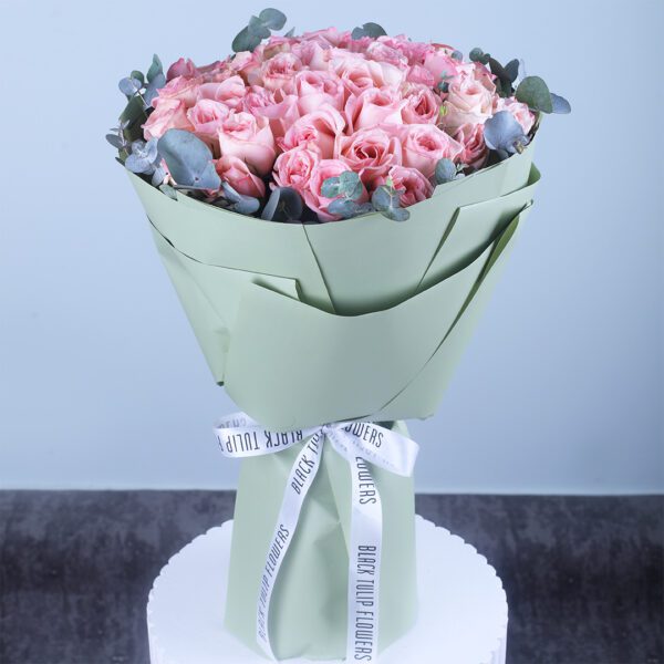 Bouquet of 50 fresh pink roses wrapped in sage green paper with white ribbon
