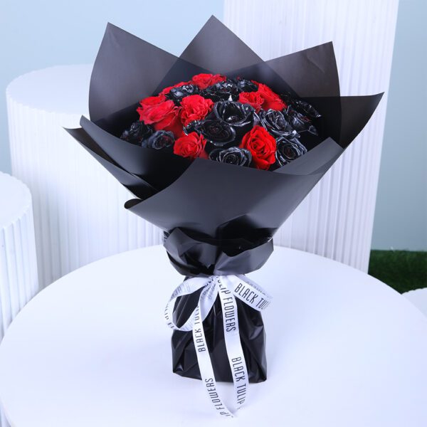 A bouquet with black painted and red roses wrapped in black tied with a white ribbon.