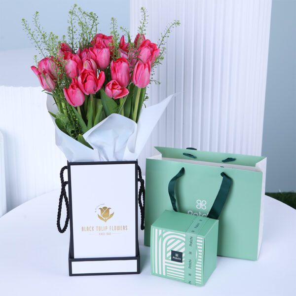Pink tulips arranged in a white wrap with Patchi chocolates and gift bags