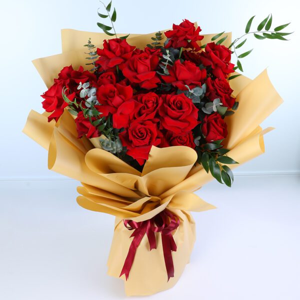 Bouquet of 15 red roses with green foliage wrapped in elegant golden paper