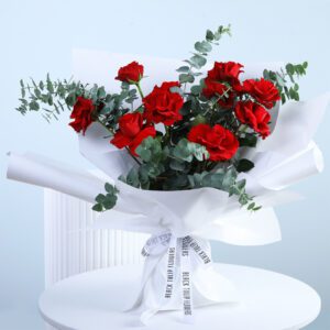 Ten red roses surrounded by green leaves, a romantic gesture capturing love in full bloom wrapped in white sheet.