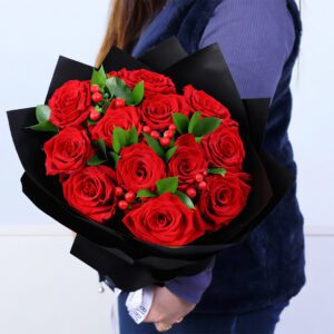 Valentine bouquet of 12 red roses with hypericum berries and ruscus foliage, elegantly arranged